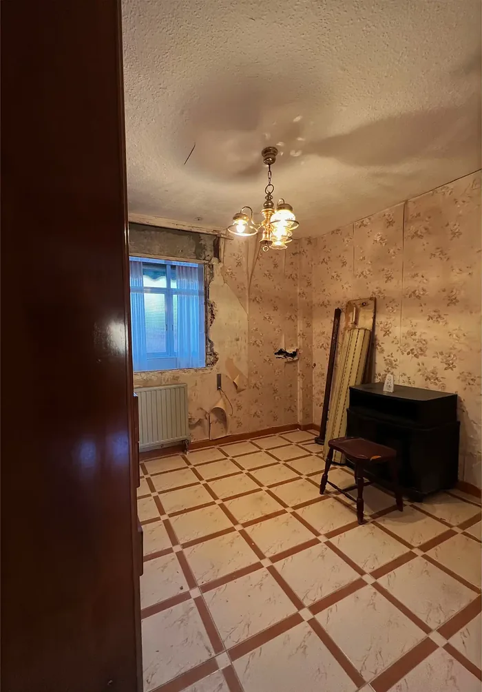 Dormitorio antes de la reforma, con papel pintado deteriorado