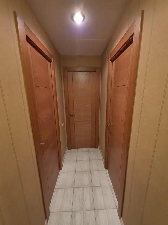 Pasillo con puertas de sapelly y revestimiento de madera
