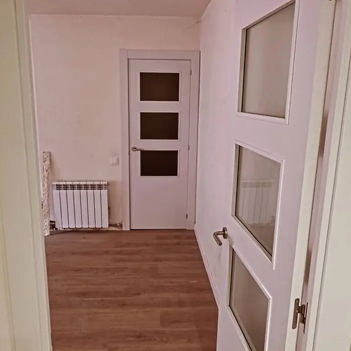 Puerta abatible lacada en blanco con cristaleras y suelo laminado
