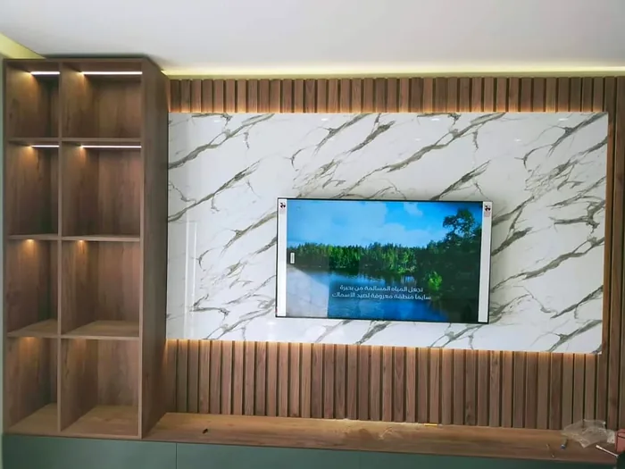 Mueble de TV a medida con revestimiento de madera, mármol e iluminación LED